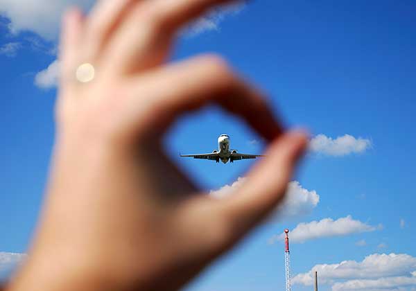 child peeps at a plane through their fingers, traveling tips will help keep them happy and enjoying the journey