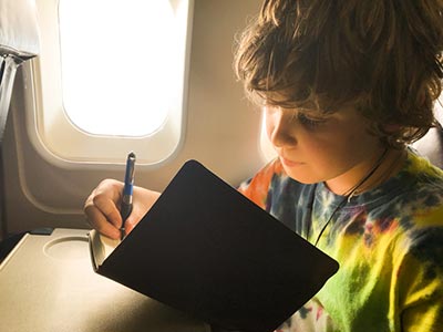 child writing in their travel journal
